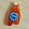 A single smoked sausage log with a blue circular 'Bottarga Australia' label, placed on a light beige marble surface.