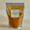 A stand-up pouch of Portside Bouillabaisse Sauce, filled with orange-brown sauce and topped with realistic ice graphics, set on a light marble countertop against a tiled background.