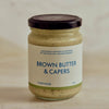 A glass jar of Portside Brown Butter & Capers with a dark brown lid and a white label featuring blue text, set against a soft beige background.