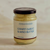 A glass jar of Portside Confit Garlic & Miso Butter with a dark lid and cream label, set on a light marble surface.