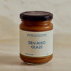 A glass jar of Portside Den Miso Glaze with a cream-colored label and a black lid, set against a neutral beige background.