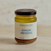 A glass jar of Portside Ginger Dressing with a cream label and dark lid, set against a soft beige marble background.