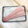A raw, skinless fillet of white fish placed on white Portside paper inside a rectangular metal tray, set on a light marble surface.