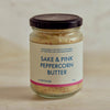 A glass jar of Portside Sake & Pink Peppercorn Butter with a cream-colored label and a dark lid, set against a neutral, light beige background.