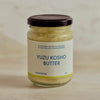 A glass jar of Portside Yuzu Kosho Butter with a cream-colored label and a dark lid, set against a neutral, light beige background.