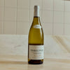 A bottle of Chablis 1er Cru white wine from Fourchaume, standing on a light marble surface against a tiled wall.